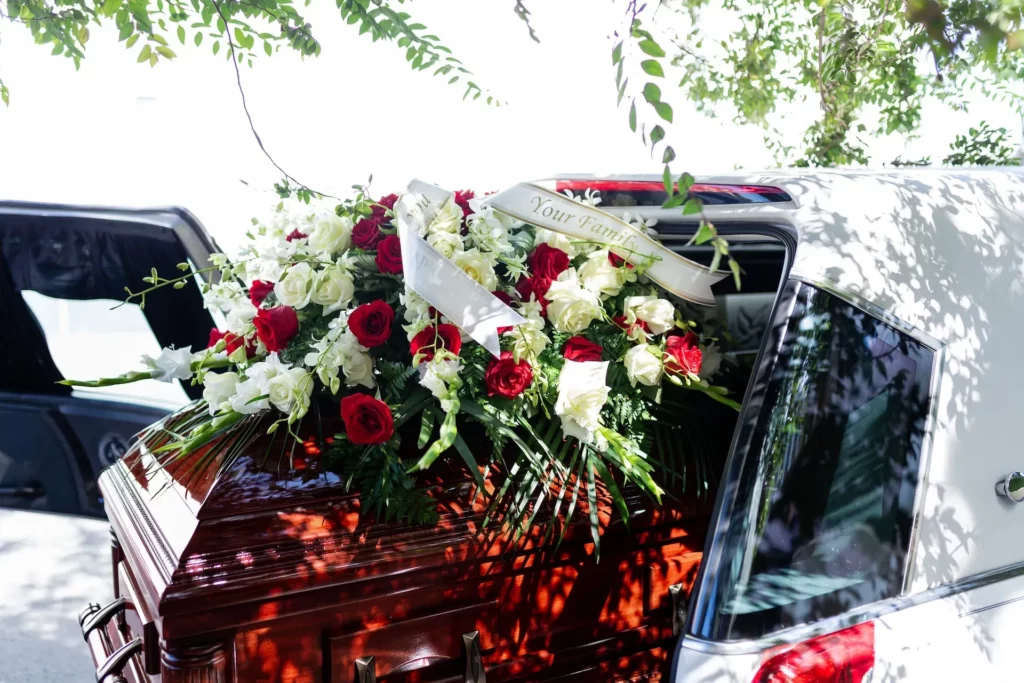 Cercueil en bois massif orné d'un grand bouquet de roses rouges et blanches.