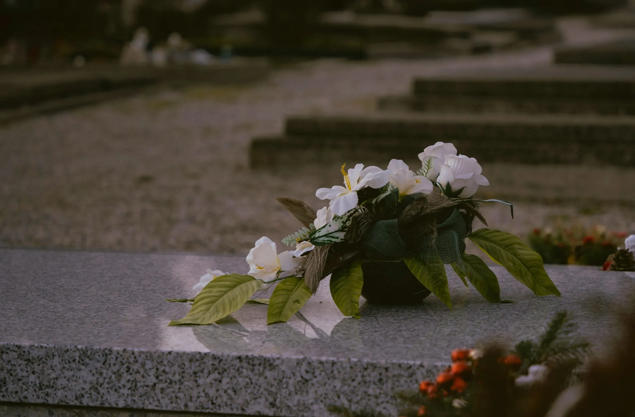 Composition de fleurs blanches déposée sur une pierre tombale en granit au cimetière.