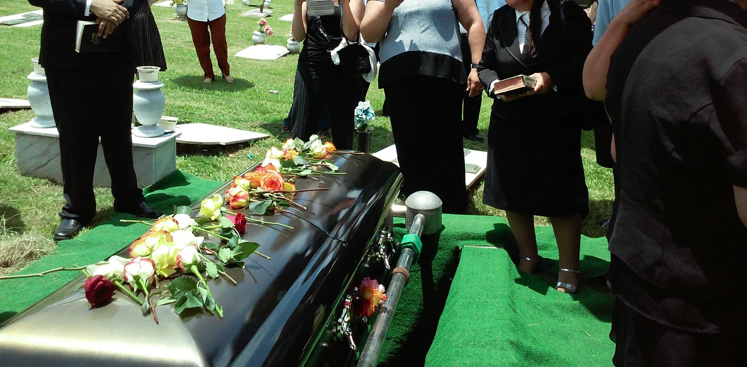 Cercueil sombre décoré de fleurs lors d'une cérémonie d'enterrement au cimetière.