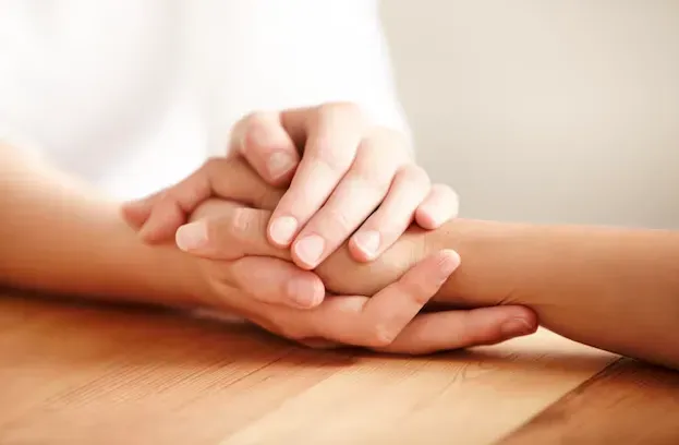 Deux personnes se tenant les mains en signe de soutien et de réconfort après un deuil.