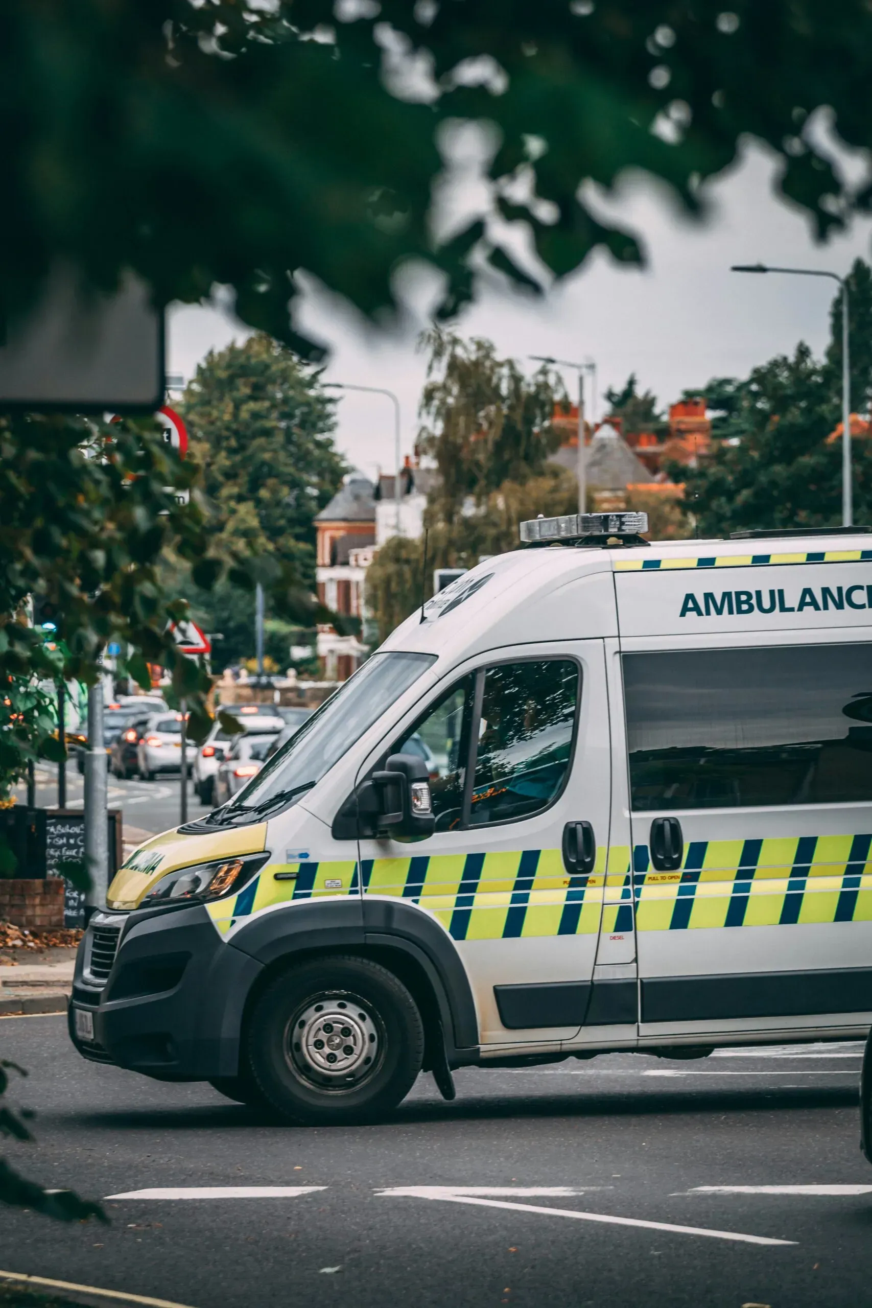 Véhicule d'ambulance blanc et jaune circulant sur une voie urbaine.